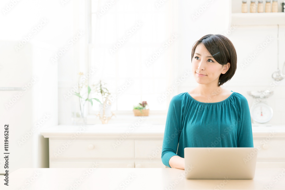 young asian woman using laptop in the kitchen young asian woman using laptop in the kitchen