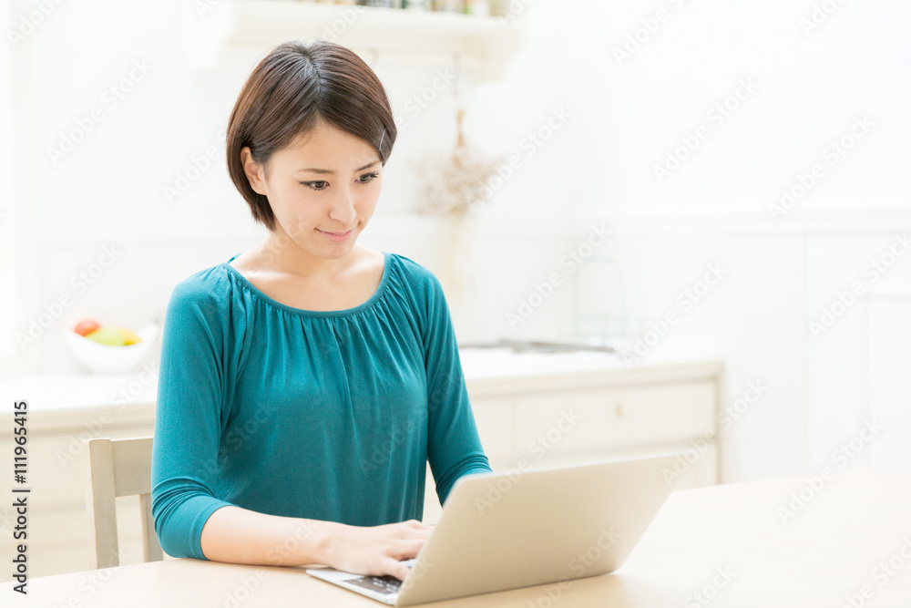 young asian woman using laptop in the kitchen young asian woman using laptop in the kitchen
