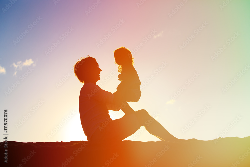 Father and little daughter playing silhouettes at sunset