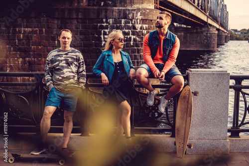 Sexy blond female and two casual males with long board posing ne