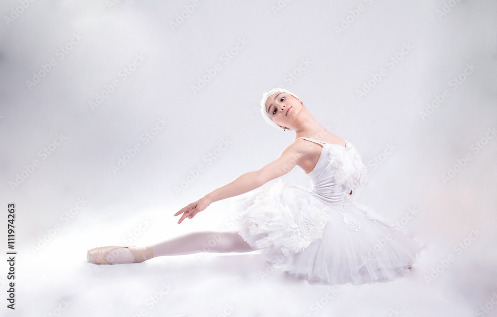 Young ballerina in white  is dancing on a white background