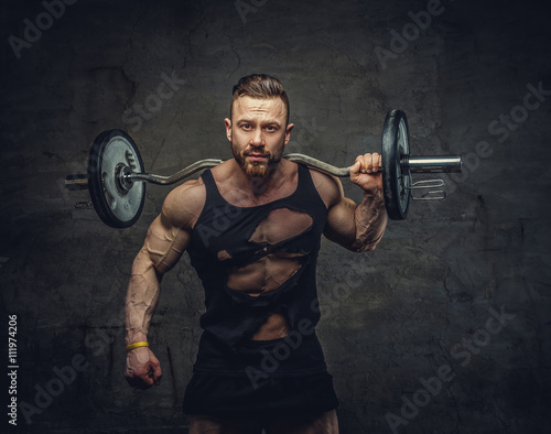 Portrait of bearded bodybuilder with barbell on his shoulder.