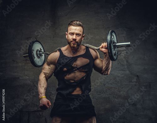 Portrait of bearded bodybuilder with barbell on his shoulder.