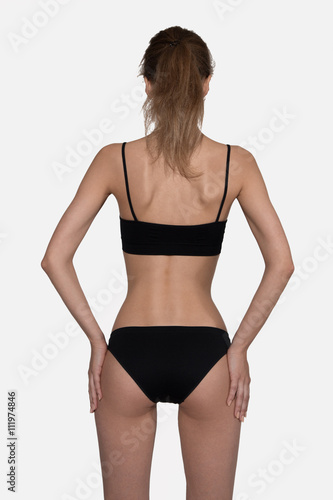 Slim woman in black back to camera with hands on hips isolated on