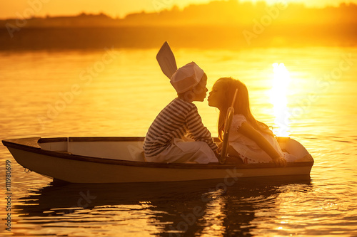 Boy with a girl floating on a boat rowed across the lake