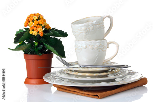 Fototapeta Naklejka Na Ścianę i Meble -  cups, plates and saucers on the cloth on a white isolated background with a flower and Cutlery
