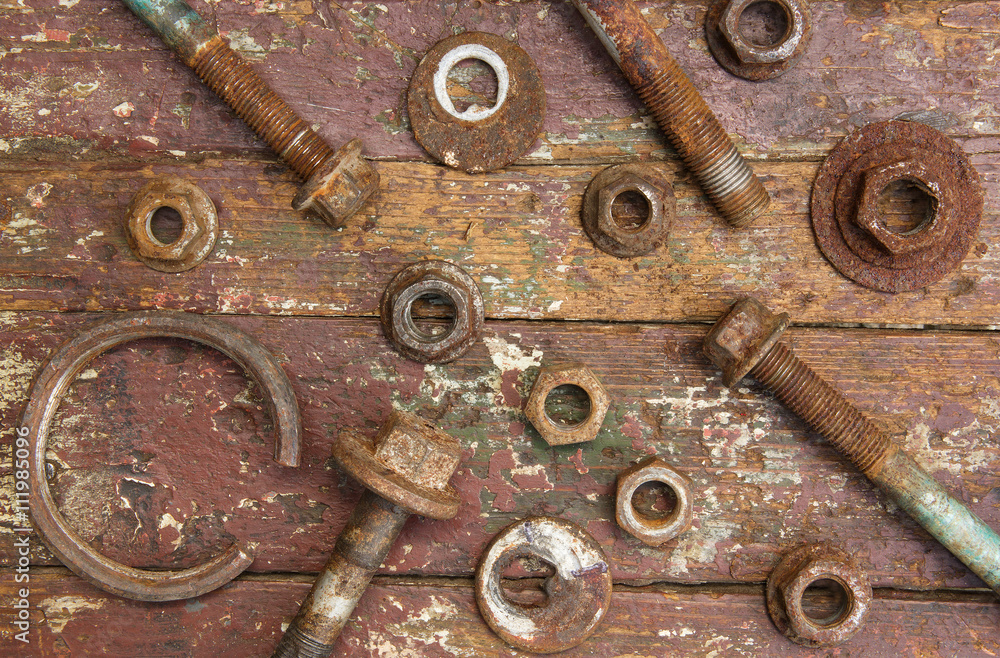 Set of rusty washers,  bolts, nuts on wooden background.