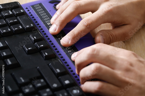 Blind person using computer with braille computer display photo