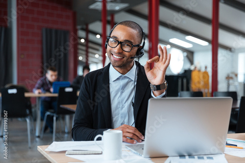 Bild auf Leinwand Businessman wearing headphones and showing okay sign