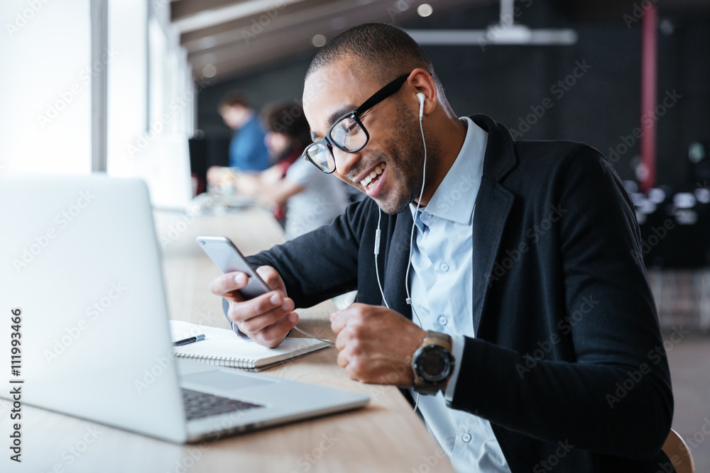Smilling cheerful businessman texting message on the smartphone Smilling cheerful businessman texting message on the smartphone