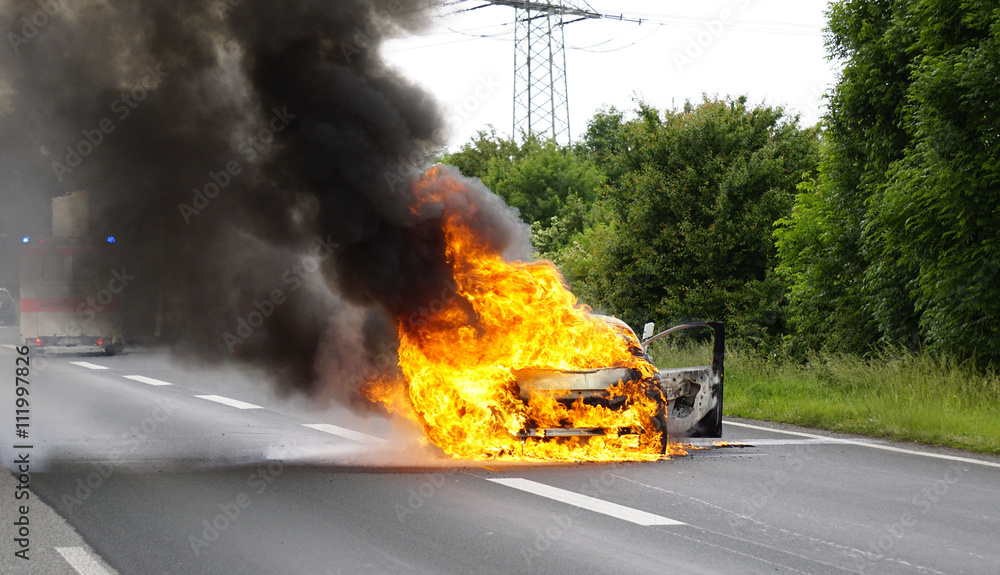 Fototapeta premium Ein Auto brennt lichterloh auf der Autobahn