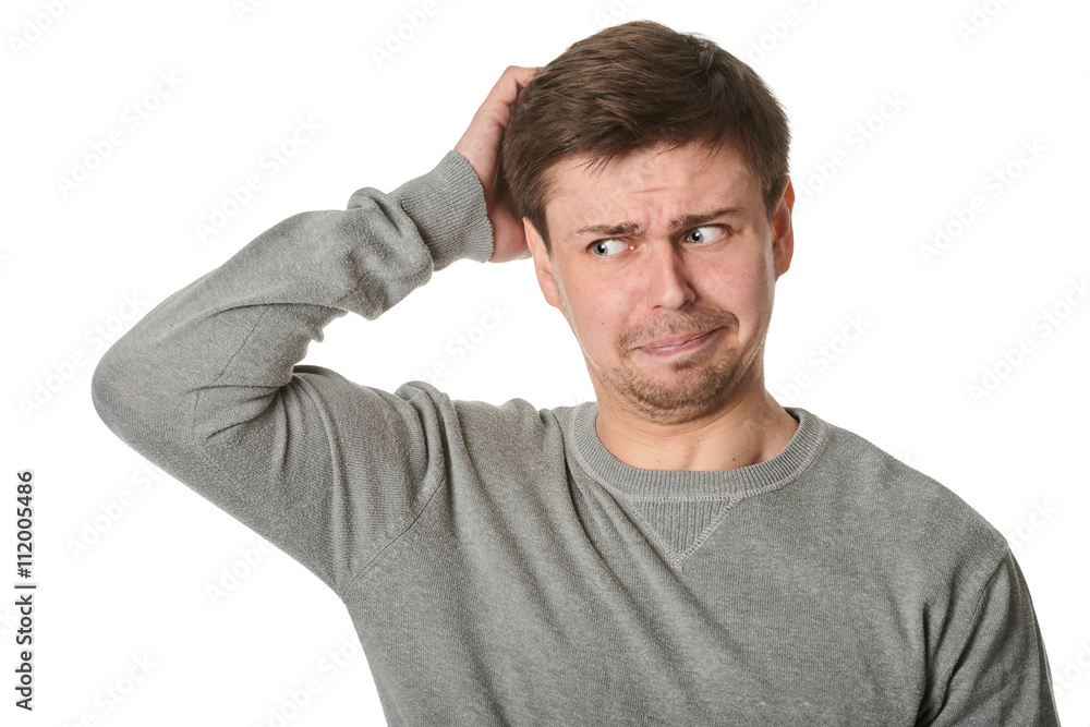 Happy young man with uncertain puzzled expression, on gray background Happy young man with uncertain puzzled expression, on gray background