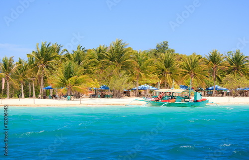 Tropical coast, beach with palm trees and boat. Philippines.