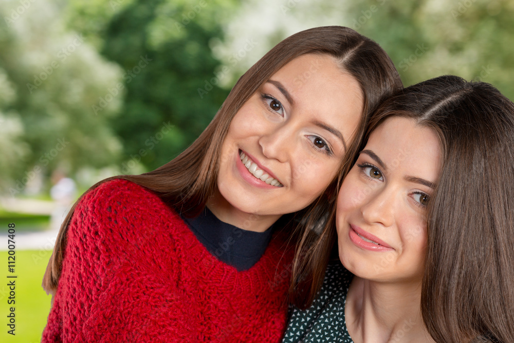 Obraz premium Two beautiful sisters hugging each other and smiling