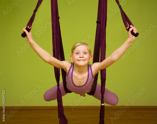 Little girl making aerial yoga exercises, indoor
