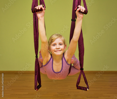 Little girl making aerial yoga exercises, indoor