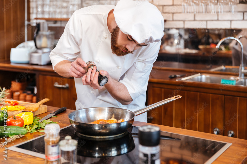 Concentrated chef cook cooking salmon steak on frying pan Concentrated chef cook cooking salmon steak on frying pan
