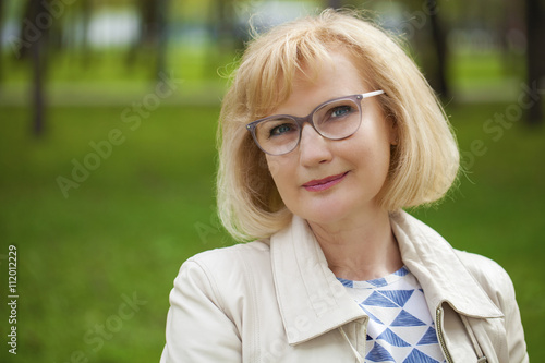 Close up portrait of lovely middle aged woman in the summer park © Andrey_Arkusha