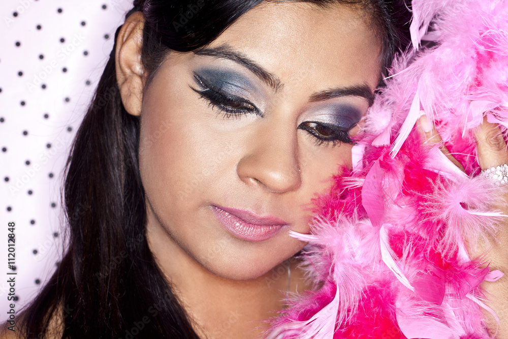 head shot of a attractive female with her face close to pink feathers. head shot of a attractive female with her face close to pink feathers.