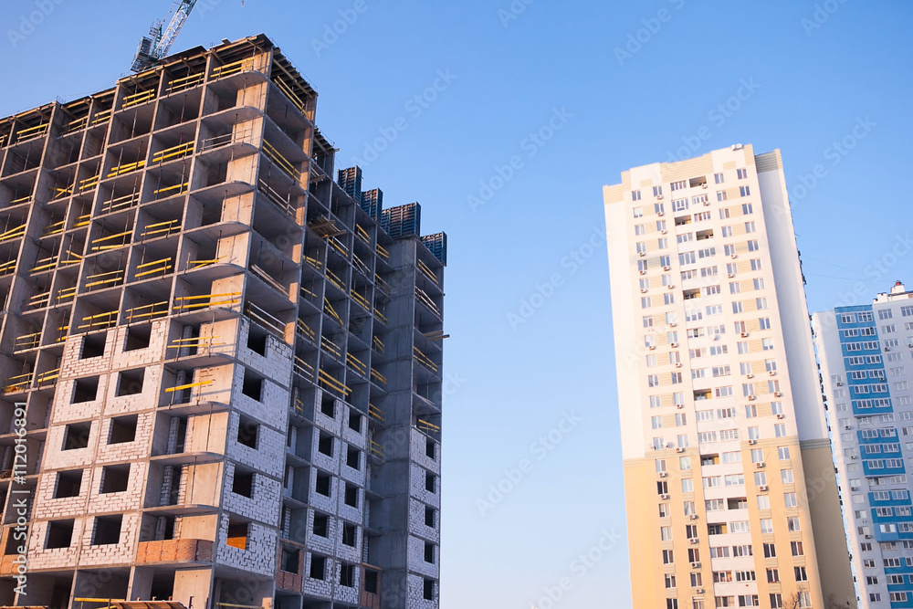 Fototapeta premium construction of multi-storey building with a crane on top, unfinished house