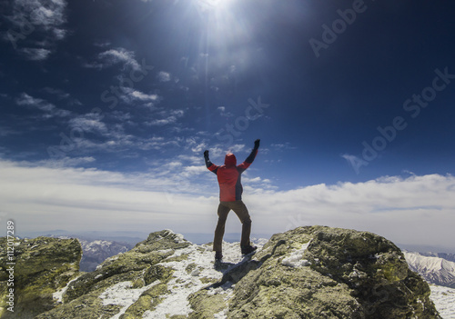 man standing on a cliff in mountains with hands up
