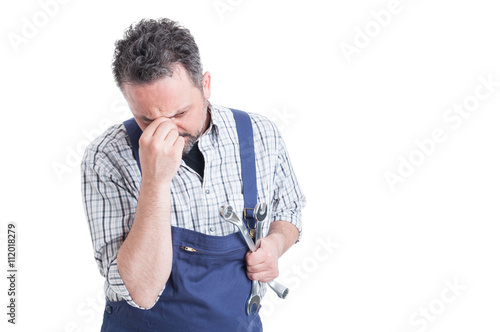 Stressed repairman thinking how to fix a problem