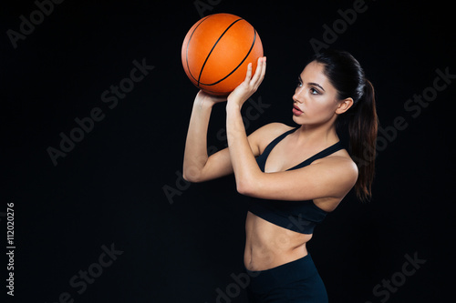 Focused pretty woman athlete standing and throwing basketball ball
