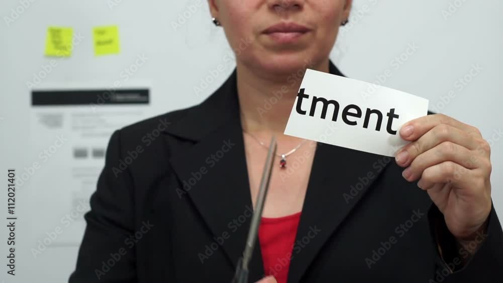 Female office worker or business woman cuts a piece of paper with the word investment on it as an investment reduction business concept. Female office worker or business woman cuts a piece of paper with the word investment on it as an investment reduction business concept.