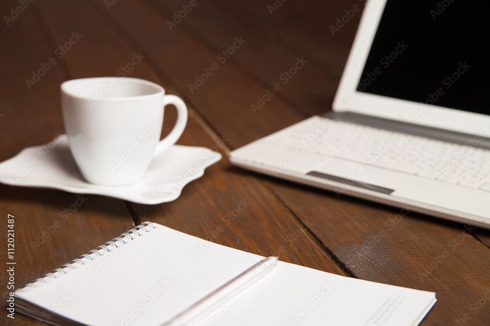 Cup of coffee,notebook and laptop on table Cup of coffee,notebook and laptop on table