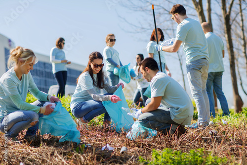 volunteers with garbage bags cleaning park area photo