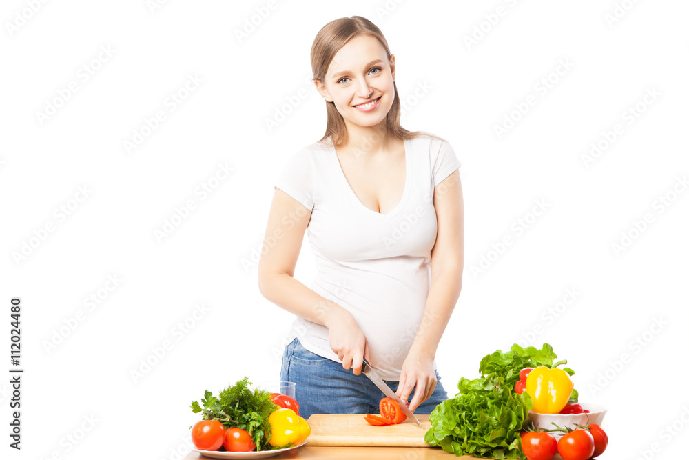 Pregnant woman cutting tomato on board Pregnant woman cutting tomato on board