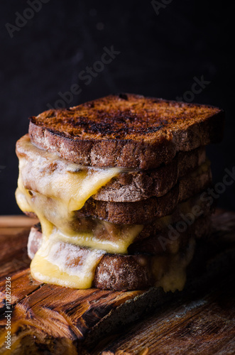 Canvas Print Brown bread toasts with grilled cheese on dark wooden background