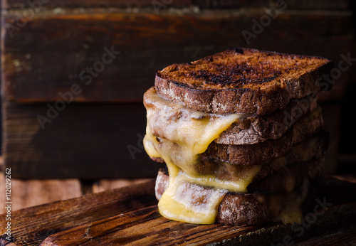 Foto Brown bread toasts with grilled cheese on dark wooden background