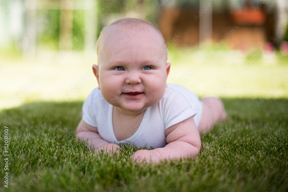 baby is lying on the grass in the garden and smiling baby is lying on the grass in the garden and smiling