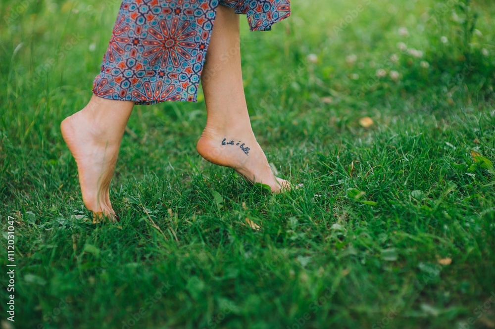 Woman legs walking on green grass Woman legs walking on green grass