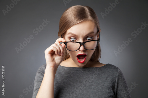 Canvastavla Wide-eyed woman in glasses looking down in amazement