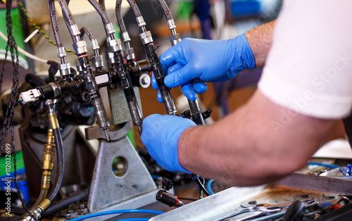 Professional mechanic testing diesel injector in his workshop. photo