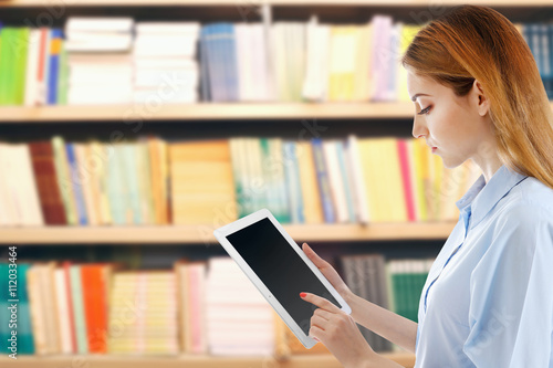 Young woman holding tablet-pc in library