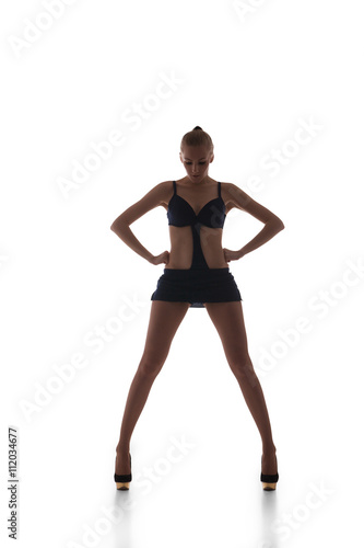 Beautiful slim go-go dancer in black dress with wide legs looking down