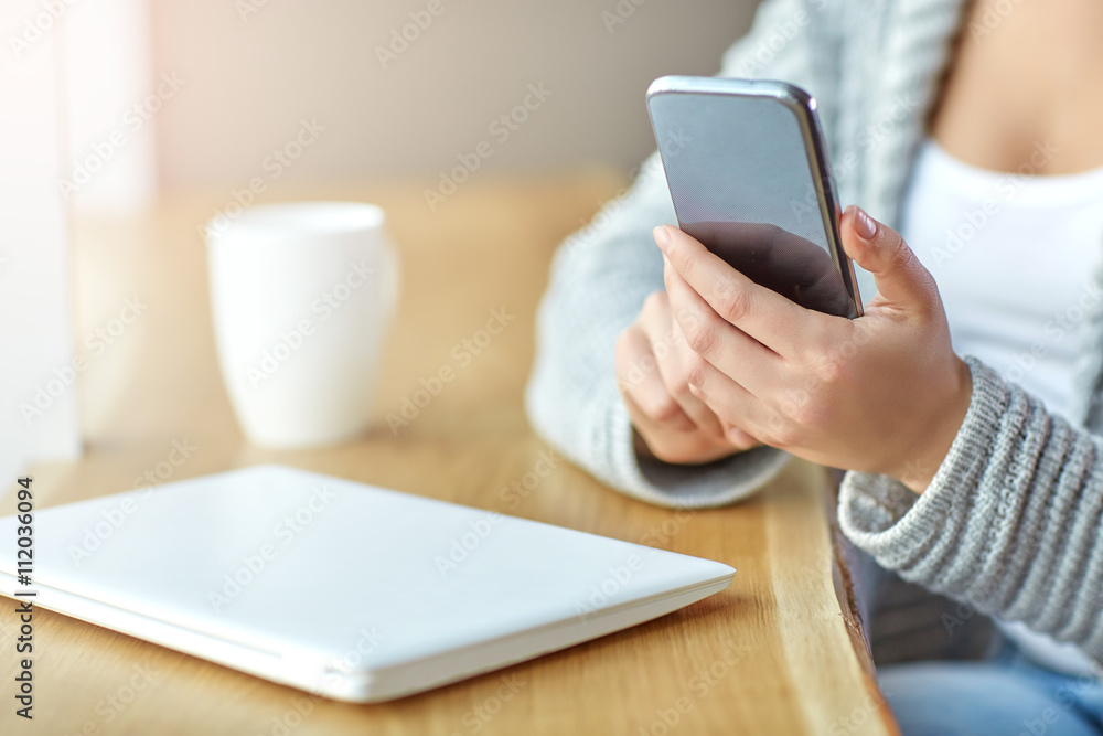 Woman holding a phone in hands and writes the message at the cafe. Close up Woman holding a phone in hands and writes the message at the cafe. Close up