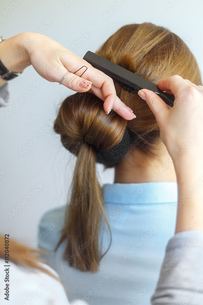 Fototapeta premium Professional female hairdresser making hairstyle to cheerful young woman with long hair