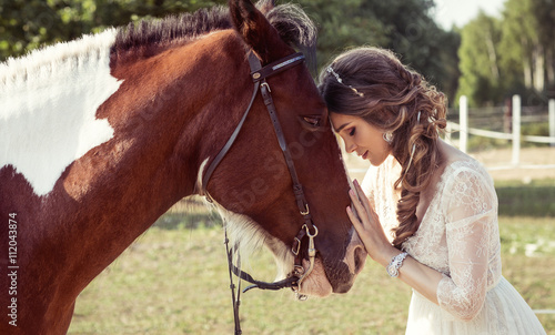 Portrait of beautiful young bride hugging a horse