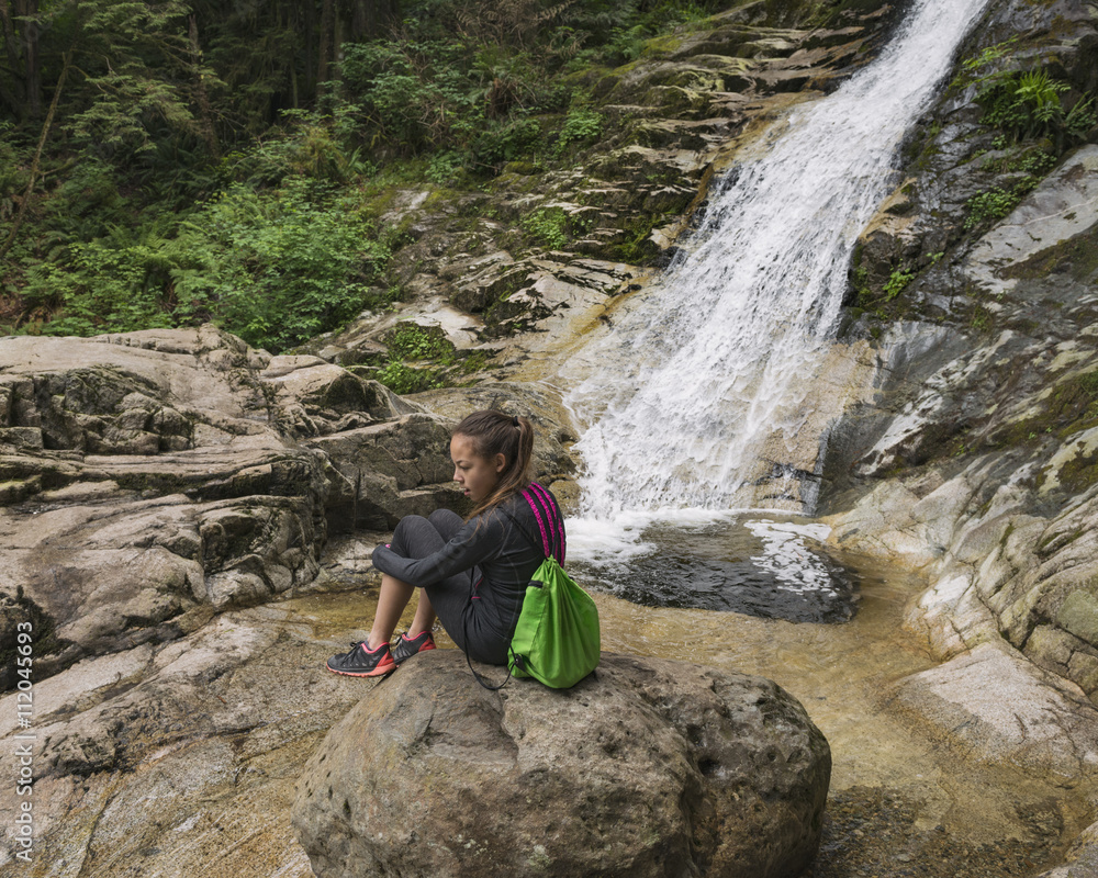 Girl Sitting On Rock By Waterfall
