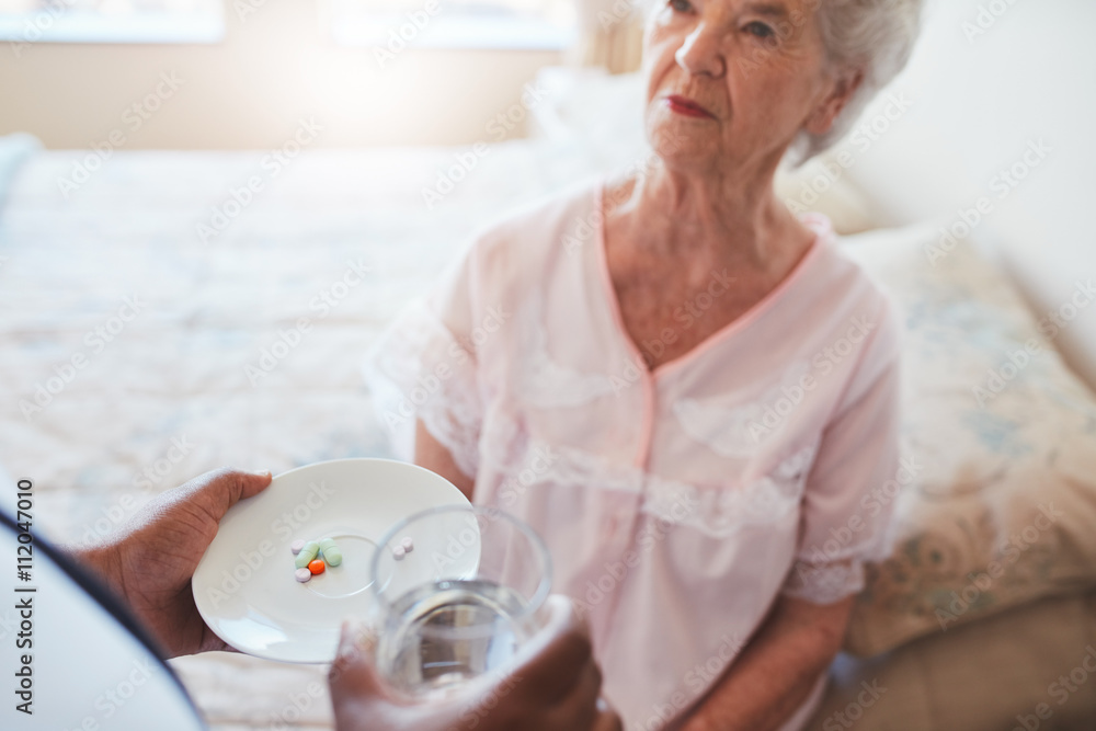 Hand of nurse giving pills to elderly female patient Hand of nurse giving pills to elderly female patient