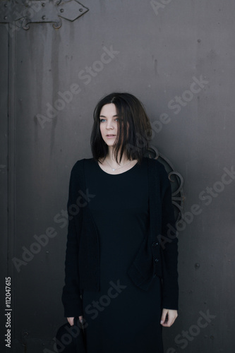 Young woman wearing black clothes posing near gates