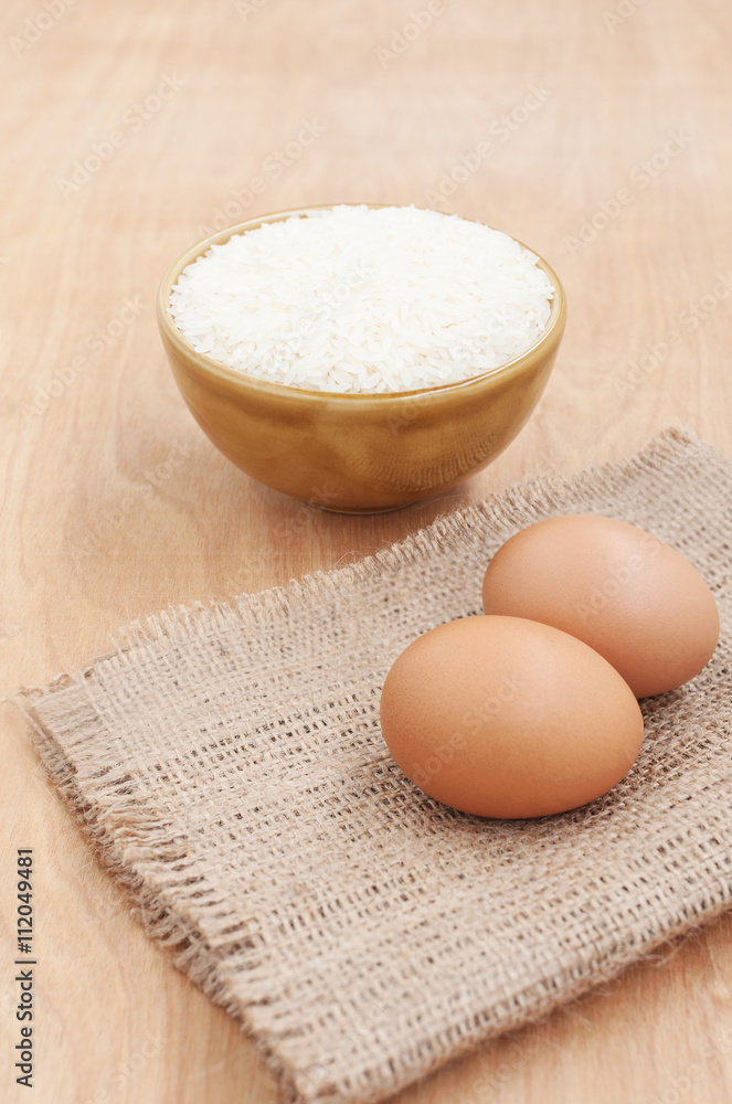 White rice in brown bowl with egg on wooden White rice in brown bowl with egg on wooden
