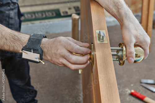  Carpenter installing door knob, close up human hend hold doorha photo