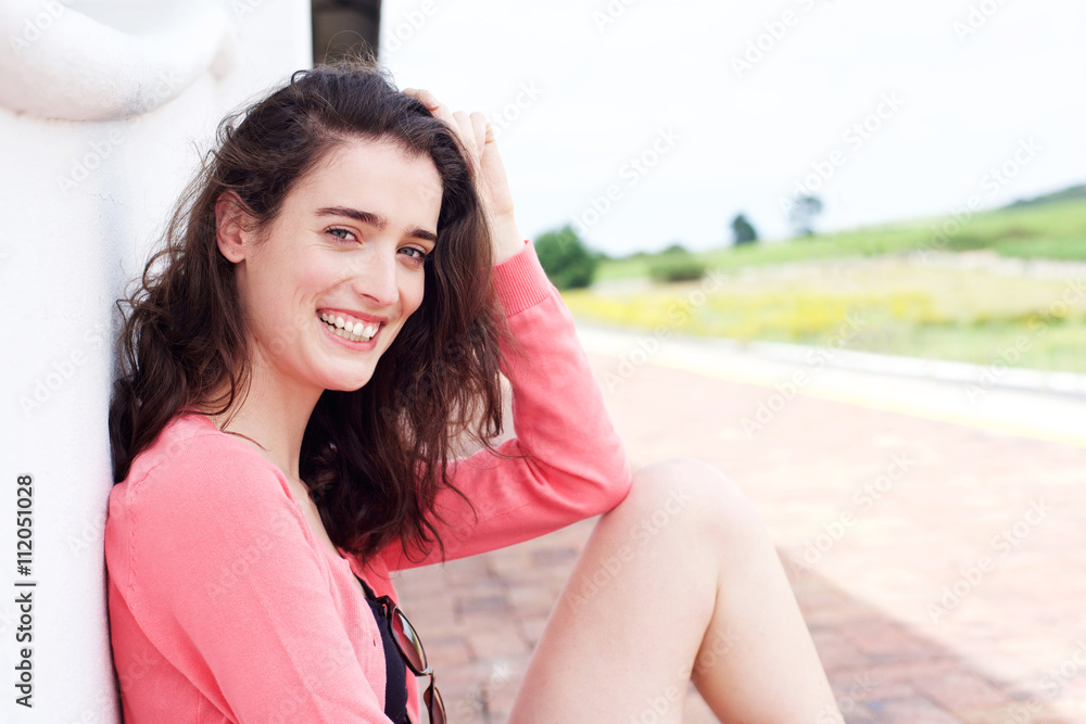 Fototapeta premium Attractive woman sitting outside with hand in hair