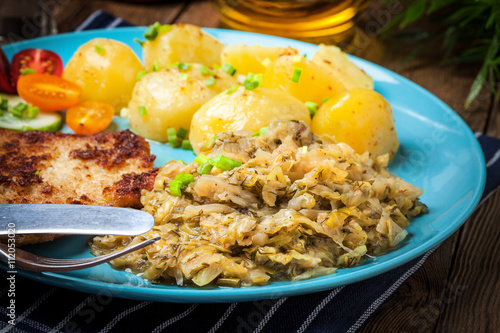 Fried pork chop, baked potatoes and fried young cabbage.