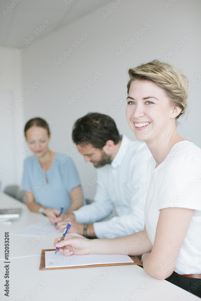 Smiling colleagues writing on paper in office Smiling colleagues writing on paper in office